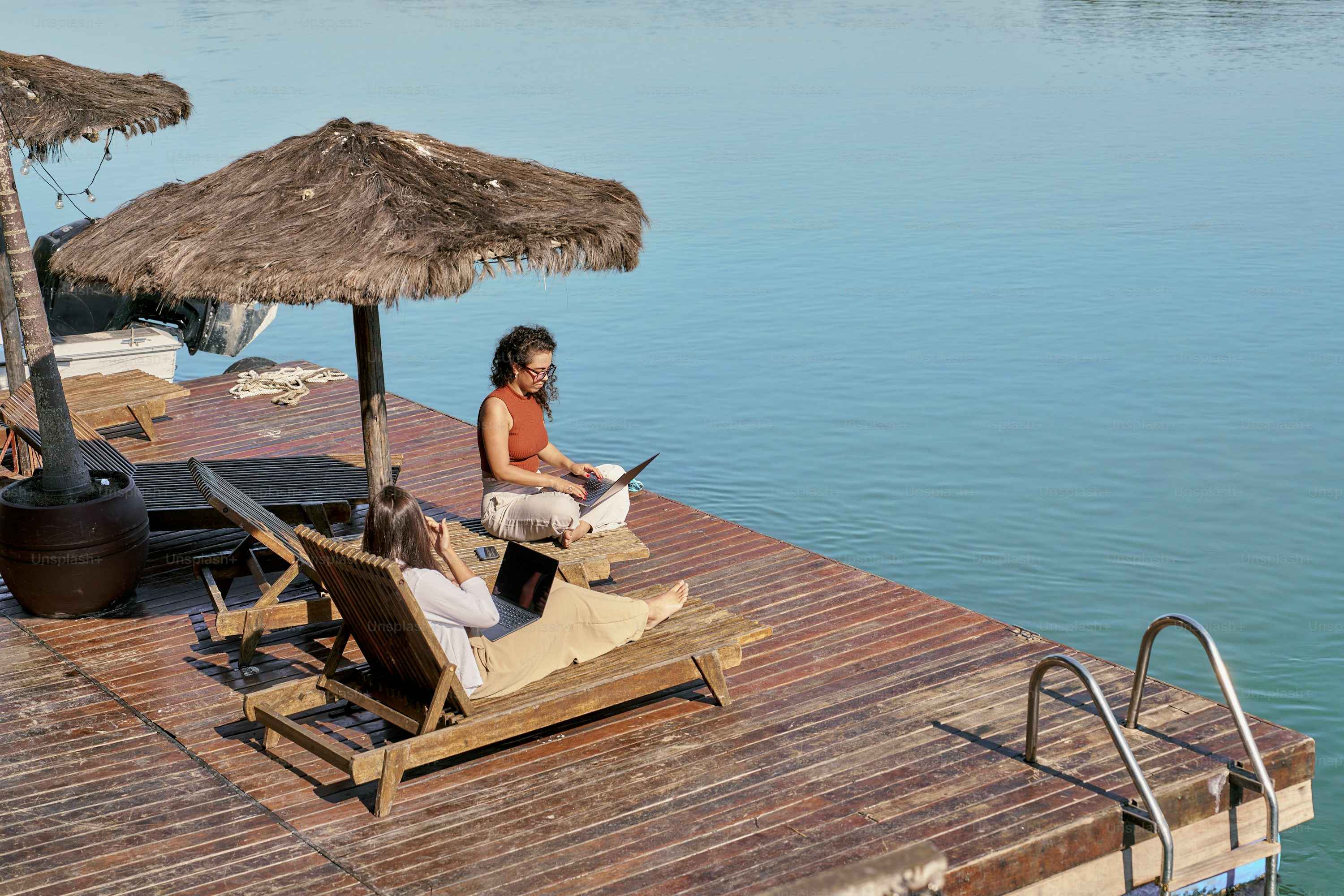 Woman sitting on lounge chair next to water
